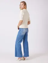 Buzo tejido color beige, marca Nanette, con cuello a la base y solapa decorada con apliques de perlas. Tiene manga corta con puño y ruedo acanalado.