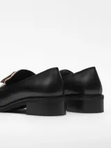 Mocasín negro de cuero con detalle de tela beige en el empeine y tacón bloque.