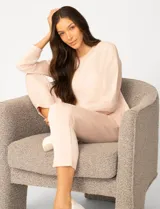 Buzo de punto color rosa, con cuello redondo y detalle de tejido crochet en el escote. Presenta mangas largas y un corte clásico con caída suave.
