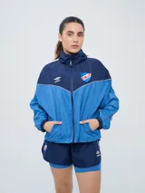 Campera deportiva Umbro del Club Nacional de Football, modelo Sky para mujer. Diseño en tonos azul marino y celeste con detalles en blanco y líneas finas rosadas, cuello alto, cierre frontal y bolsillos.