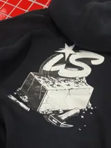 Buzo con capucha y cierre frontal, color negro, con diseño gráfico estampado en la espalda que incluye letras y un ladrillo.