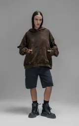 Hoodie de corte oversize y largo crop, confeccionado en algodón con efecto de desgaste y color óxido. Presenta costuras expuestas, detalles de roturas en los bordes y bolsillo frontal tipo canguro.