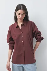 Camisa de manga larga de algodón en color blanco, con cuello clásico, cierre frontal de botones y silueta relajada.