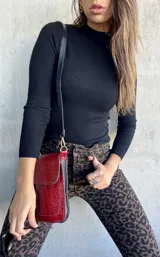 Polera negra de tejido de punto acanalado, manga larga y cuello alto.