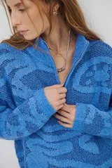 Buzo de tejido de punto con cierre frontal, cuello alto y diseño estampado en tonos beige y marrón.
