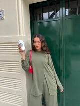 Conjunto gris melange confeccionado en lanilla, compuesto por una remera de manga larga con diseño cruzado en el frente y un pantalón largo de corte ancho con bolsillos.