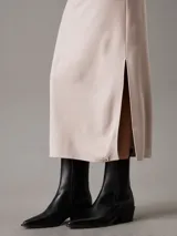 Vestido largo de punto milano color beige, sin mangas, con cuello barco, corte slim y panel trasero recortado.