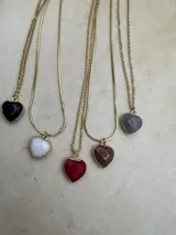 Collar con cadena dorada y dije en forma de corazón de piedra natural en varios colores: negro, blanco, rojo, marrón y gris.