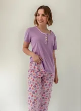 Pijama compuesto por una remera lisa de manga corta en color lila con detalles estampados en el cuello y escote, y un pantalón largo con estampado tropical y de frutas en tonos rosados y lilas.