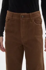 Pantalon de pana color verde oliva, de corte recto y tiro medio, con bolsillos laterales y cierre frontal.