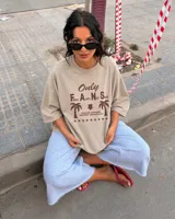 Remera oversize de color beige con estampa frontal en marrón, mangas cortas y cuello redondo.