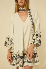 Minivestido blanco de lino con escote en V, mangas anchas acampanadas y bordados dorados en los puños, el dobladillo y el cinturón ajustable.
