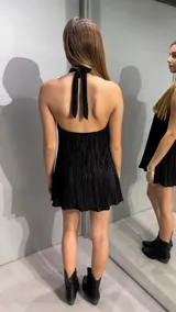 Vestido corto de color negro con textura plisada, diseño sin mangas y cuello alto tipo halter.
