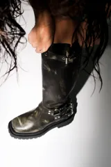 Botas de cuero marrón con efecto desgastado, caña alta, suela track y múltiples correas con hebillas metálicas.