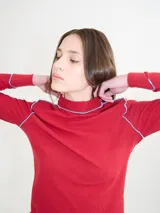 Polera de manga larga confeccionada en tela rib color bordó, con cuello alto y hombreras. Presenta costuras a la vista con pespuntes en hilo de color contrastante en el cuello, puños, hombros y ruedo.