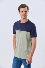 Remera de algodón y poliéster de corte clásico, con diseño en bloques de color negro en la parte superior y gris melange en la inferior. Presenta cuello redondo, mangas cortas y un pequeño estampado tipográfico en el pecho.