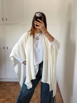 Ruana de tejido fino en color blanco, con diseño abierto y caída fluida, ideal para capas ligeras.