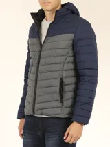Campera capitoneada con capucha, diseño color block en azul marino y gris, cierre frontal con cremallera y bolsillos laterales con cierre.