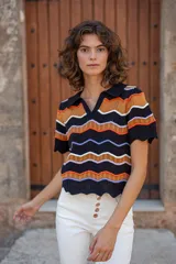 Chomba tejida de punto con cuello estilo polo y escote en V. De manga corta y calce relajado, cuenta con diseño de ondas horizontales en colores combinados: negro, naranja, blanco y lila.