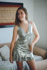 Vestido corto negro con estampado de plumas doradas, escote en V, breteles finos cruzados en la espalda, cut-outs laterales y volado en el ruedo.