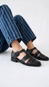 Sandalias tipo cangrejera de cuero color marrón, con diseño de tiras cruzadas y textura en la parte frontal. Cuentan con pulsera al tobillo con hebilla metálica y taco bajo.