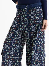 Pantalón de corte wide leg con diseño cargo, confeccionado en guipiure de denim azul con estampado floral. Presenta bolsillos laterales tipo cargo y cierre frontal.