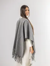 Ruana gris de tejido de punto con flecos en el ruedo.