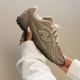 Championes New Balance modelo 204L en tono beige, confeccionados en gamuza con detalles de costuras y logo lateral característico de la marca. Presenta suela de goma texturizada y cierre mediante cordones.