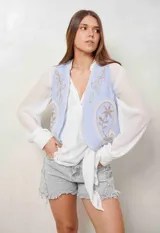 Chaleco blanco de corte corto, con bordados florales en tono tostado en la parte delantera.