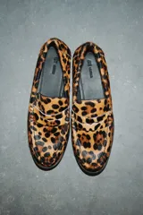 Mocasines de cuero con textura de pelo y estampado de leopardo, con diseño clásico de lengüeta decorativa y costuras frontales.