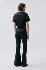 Pantalón negro de corte ajustado con aberturas en el ruedo.