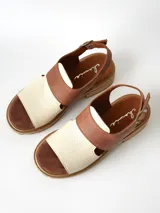 Sandalias de cuero combinadas en color marrón y crudo, con suela track y taco bajo. Tienen tira ajustable con hebilla en el talón.