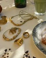 Anillo de diseño orgánico y macizo con forma irregular, elaborado en metal con acabado brillante. Presenta una estructura abierta que permite su ajuste.