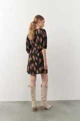 Vestido corto con estampado animal print en tonos beige y negro. Tiene mangas tres cuartos con elástico, cut-out en el frente y lazo.