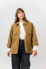 Sobrecamisa de gabardina liviana color crema, con corte oversize, cuello clásico, cierre frontal con botones a presión y dos bolsillos delanteros con solapa.