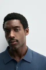 Polo de punto canalé color rosado, de corte regular fit, con cuello solapa y cierre frontal de botonadura. Manga corta y acabados en rib.