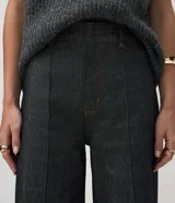 Pantalón wide leg de tiro alto confeccionado en denim de algodón. Presenta una pretina tipo sastrería con presillas, cierre frontal con botón y cremallera, bolsillos funcionales y nervaduras frontales que definen la silueta.