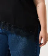 Blusa de manga corta con escote redondo, confeccionada en algodón. Presenta un diseño alargado con un detalle de encaje irregular aplicado en el ruedo, aportando un acabado asimétrico y delicado.