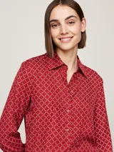 Blusa roja con estampado de rombos blancos, cuello con lazo y mangas largas con puños abotonados.