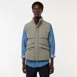 Chaleco acolchado puffer color gris, sin mangas, con cuello alto, cierre frontal de cremallera con solapa de botones a presión y bolsillos laterales amplios.