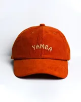 Gorro de pana color naranja con visera y bordado frontal con la palabra "Yamba" en color crema.