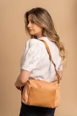 Bandolera de diseño práctico con combinación de texturas en tonos tierra, confeccionada en tela y símil cuero. Cuenta con un compartimento principal con cierre, un bolsillo frontal con cierre y correa ajustable para llevar al hombro o cruzada.