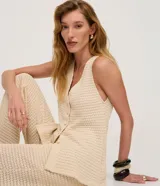 Chaleco de punto color beige claro, con cuello en V y cierre frontal de botones. El tejido presenta un patrón texturizado de pequeños puntos.