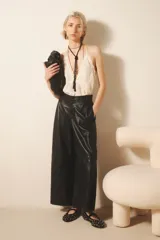 Pantalón de cuero ovino negro, de corte amplio con pierna ancha, pinzado y con acceso delantero de snaps metálicos y cierre. Incluye tiras regulables en la cintura y bolsillos laterales.