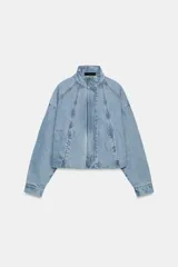 Cazadora tipo bomber confeccionada en denim de lavado claro, con cuello subido, manga larga y cierre frontal con cremallera y botones a presión ocultos. Presenta costuras verticales decorativas y bajo con ajuste elástico.