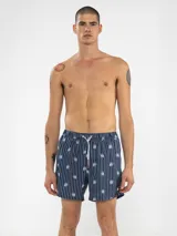 Short de baño celeste con rayas verticales blancas y estampado de flores blancas.