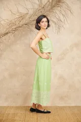 Conjunto de dos piezas compuesto por un crop top de breteles anchos y una pollera midi, ambos en color azul con detalles de bordado floral blanco en el ruedo y el lateral del top.