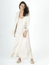 Conjunto color beige compuesto por vestido largo con breteles finos y saco con bolsillos delanteros.