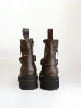 Bota corta de cuero vacuno en color chocolate con efecto desgastado. Presenta una suela track de goma negra, detalle de pulsera desmontable con tachas metálicas y cierre lateral.