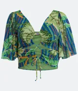 Blusa cropped con estampado de hojas en tonos verdes y azules, escote en V, mangas acampanadas y lazo ajustable en el busto.